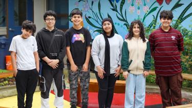 Six middle school students stand in a line, smiling at camera